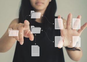 Asian woman working on virtual display monitor showing document management system (DMS), online document database and process automation to enhance efficiency of file management. Business concept
