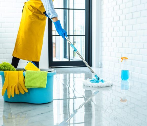 Wife housekeeping and cleaning concept, Happy young woman in blue rubber gloves wiping dust using mop while cleaning on floor at home.