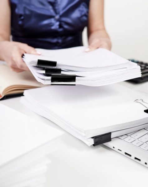An office worker moves a stack of papers fastened with Binder Clips