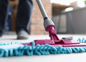 Man with mop washes floor in office. Cleaning company services concept